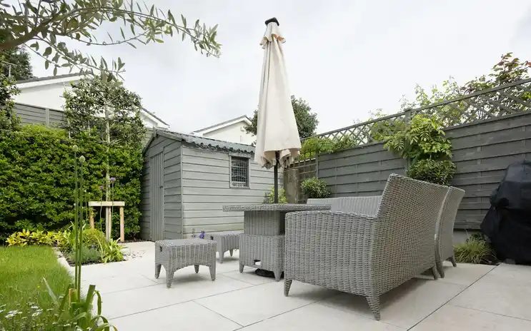 A lush, sunlit garden patio furnished for outdoor living